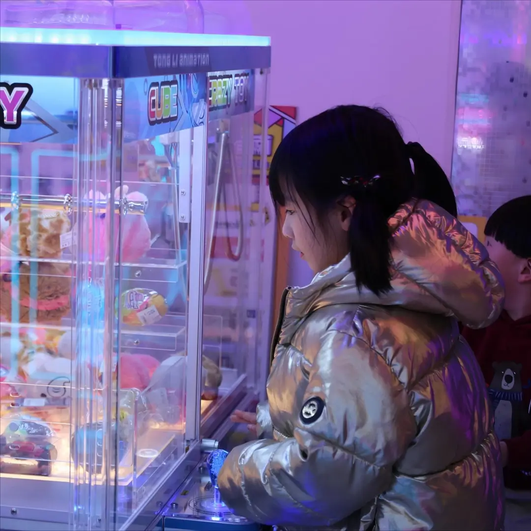 A girl playing a claw machine at Lucky Claw Birmingham