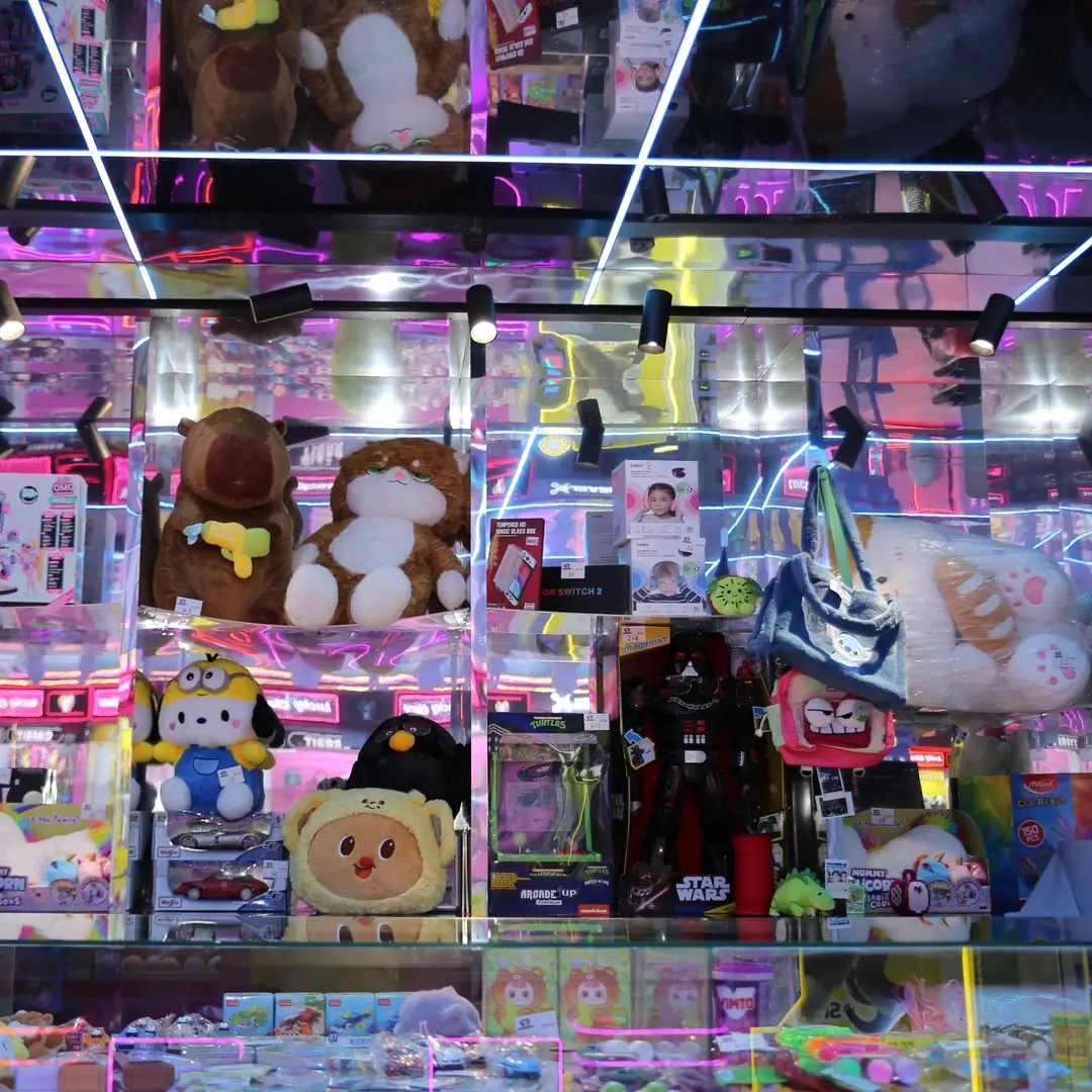 Shelves of plushies and prizes lit up in neon at Lucky Claw